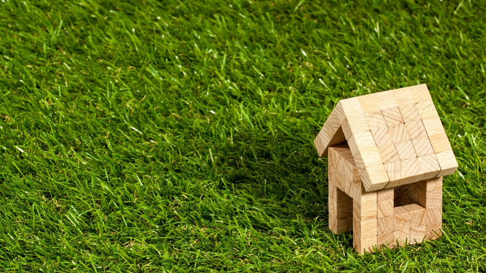 small wooden toy house in a green grass